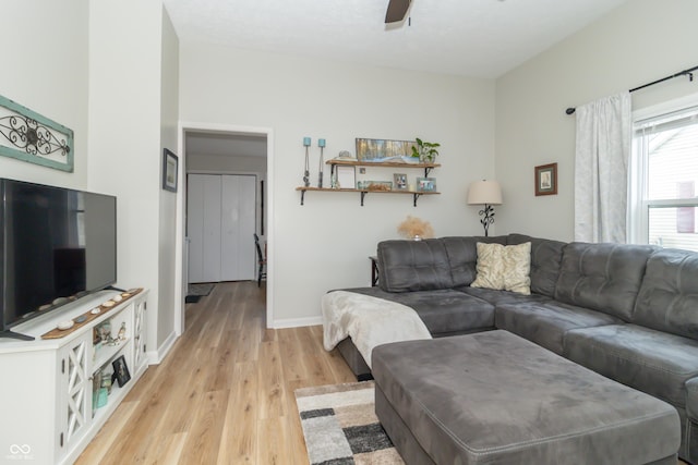 living area with a ceiling fan, baseboards, and light wood-style floors