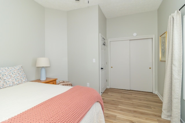 bedroom featuring a closet, light wood-style floors, and a textured ceiling