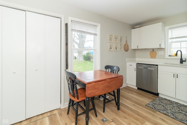 kitchen with light countertops, white cabinetry, a sink, light wood-type flooring, and stainless steel dishwasher