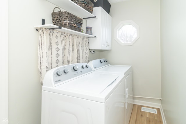 laundry area with visible vents, baseboards, light wood-style floors, cabinet space, and washer and clothes dryer