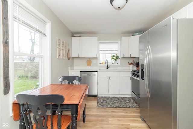 kitchen featuring white cabinetry, light wood-type flooring, a sink, and stainless steel appliances