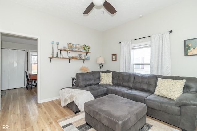 living room featuring light wood finished floors, baseboards, and a ceiling fan
