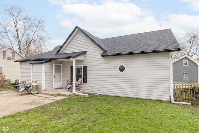 view of front of house featuring a front yard, a shingled roof, fence, and a patio area