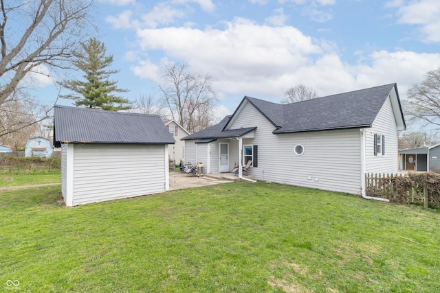 back of property with fence, an outbuilding, a patio area, and a lawn
