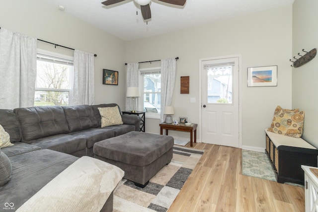 living room featuring baseboards, ceiling fan, a healthy amount of sunlight, and light wood-type flooring