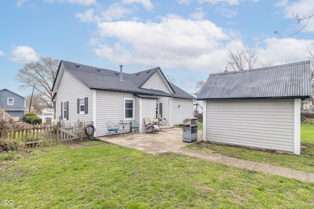 rear view of property with an outbuilding, fence, a yard, and a patio
