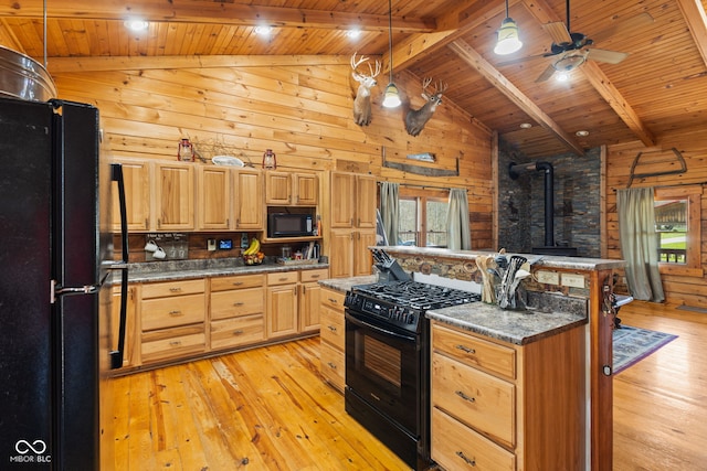 6351 Dixon Rd, Columbus, IN 47201 - kitchen with wood walls, a wood stove, light wood-style floors, beamed ceiling, and black appliances