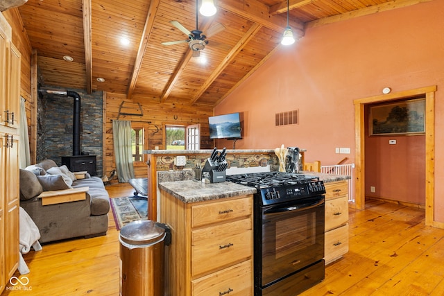 6351 Dixon Rd, Columbus, IN 47201 - kitchen with visible vents, a wood stove, light wood finished floors, and black gas stove