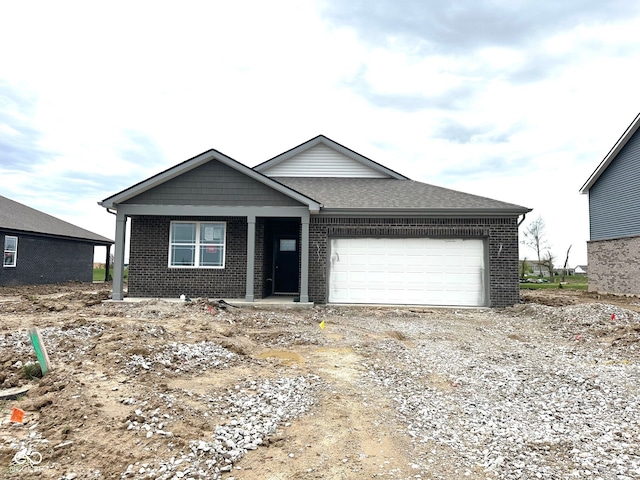 view of front of home featuring brick siding, an attached garage, roof with shingles, and driveway