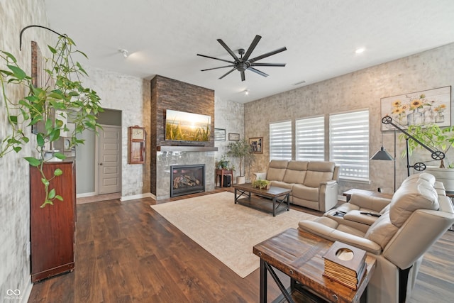 living area with dark wood-style floors, a large fireplace, and a ceiling fan