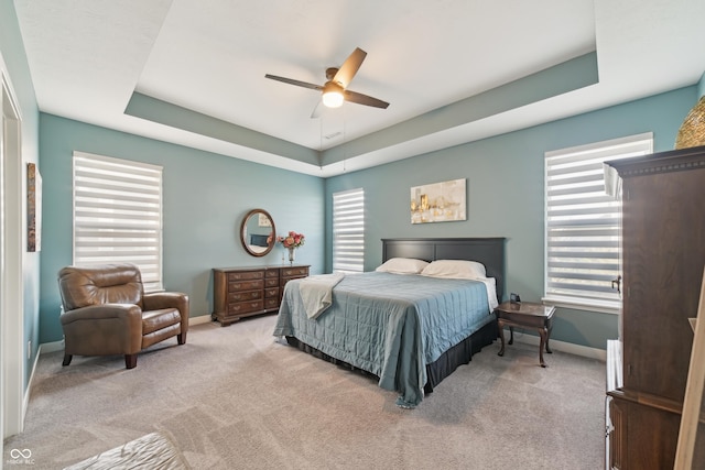 bedroom featuring baseboards, carpet flooring, a tray ceiling, and ceiling fan