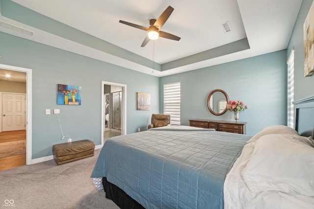 carpeted bedroom featuring baseboards, connected bathroom, visible vents, and a raised ceiling