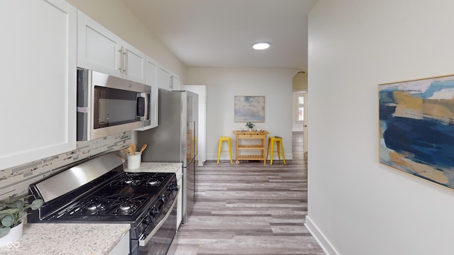 926 N Dearborn St, Indianapolis, IN 46201 - kitchen featuring white cabinets, light wood-type flooring, baseboards, appliances with stainless steel finishes, and tasteful backsplash