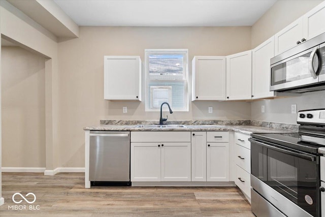 243 N Tacoma Ave, Indianapolis, IN 46201 - kitchen with stainless steel appliances, a sink, white cabinets, and light wood finished floors