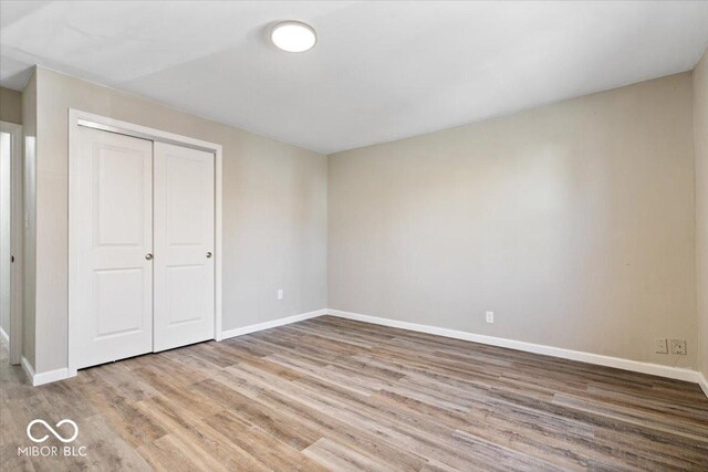 243 N Tacoma Ave, Indianapolis, IN 46201 - unfurnished bedroom featuring wood finished floors, baseboards, and a closet