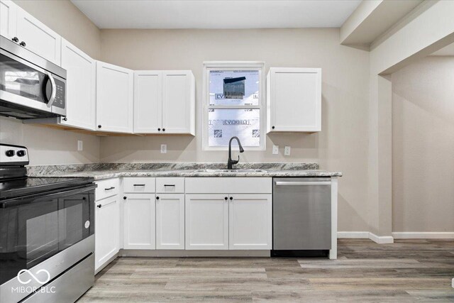 243 N Tacoma Ave, Indianapolis, IN 46201 - kitchen with appliances with stainless steel finishes, a sink, white cabinetry, light wood-style floors, and baseboards