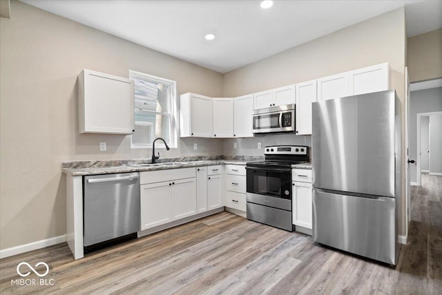 243 N Tacoma Ave, Indianapolis, IN 46201 - kitchen with stainless steel appliances, a sink, light wood-style floors, white cabinetry, and recessed lighting