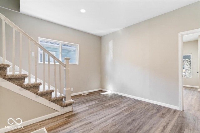 243 N Tacoma Ave, Indianapolis, IN 46201 - unfurnished living room with wood finished floors, plenty of natural light, stairway, baseboards, and recessed lighting