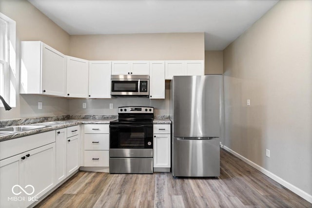 243 N Tacoma Ave, Indianapolis, IN 46201 - kitchen with stainless steel appliances, a sink, light wood finished floors, and white cabinetry