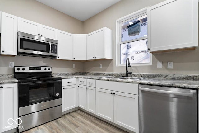 243 N Tacoma Ave, Indianapolis, IN 46201 - kitchen with appliances with stainless steel finishes, a sink, light wood-style floors, and white cabinetry