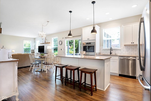 kitchen featuring open floor plan, a sink, dark wood-style flooring, and appliances with stainless steel finishes