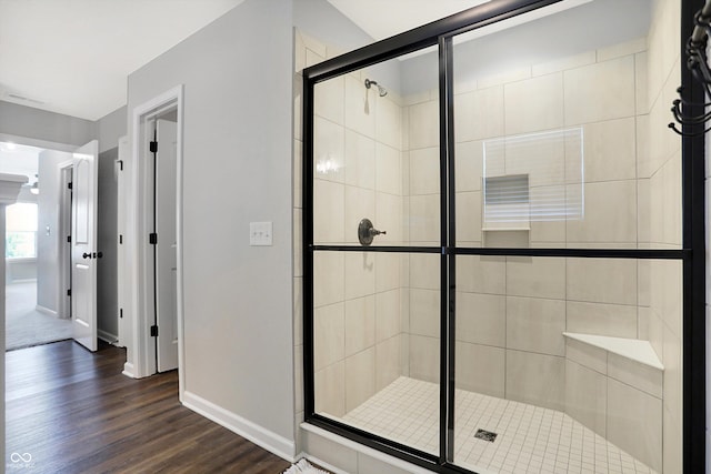 full bath with a stall shower, baseboards, and wood finished floors