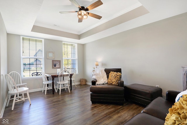 living area featuring a raised ceiling, dark wood-style flooring, visible vents, and ceiling fan