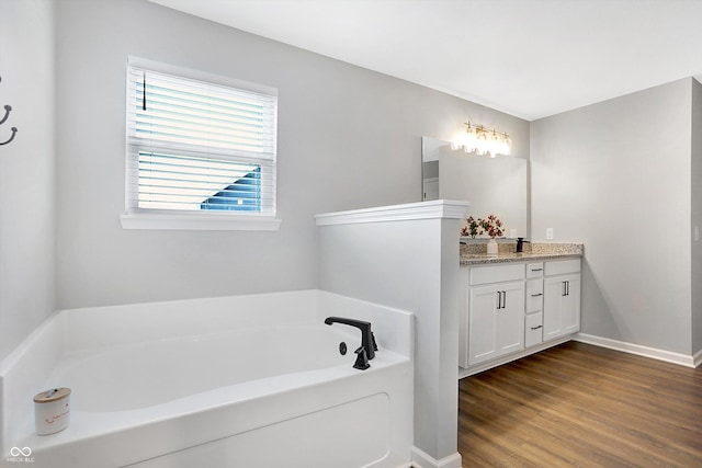 full bath with a bath, baseboards, wood finished floors, and vanity