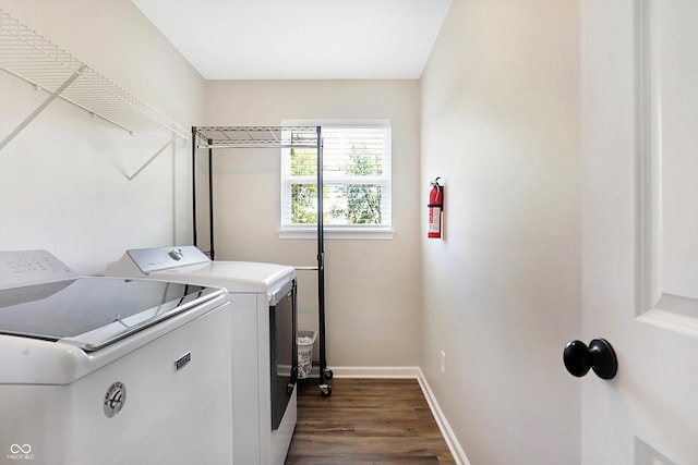 clothes washing area featuring baseboards, washing machine and dryer, laundry area, and dark wood finished floors