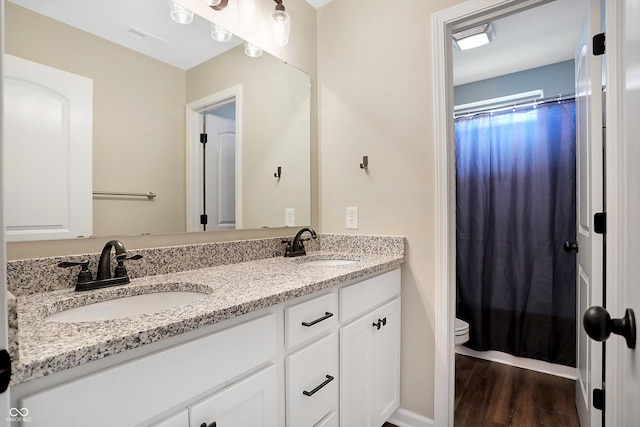 bathroom with toilet, visible vents, wood finished floors, and a sink