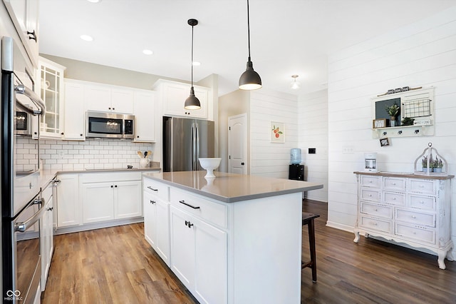 kitchen with dark wood-style floors, a breakfast bar area, decorative backsplash, and stainless steel appliances