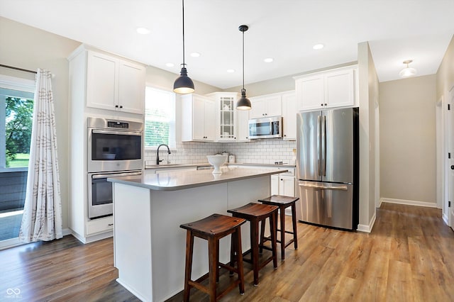 kitchen with tasteful backsplash, white cabinets, a sink, and stainless steel appliances