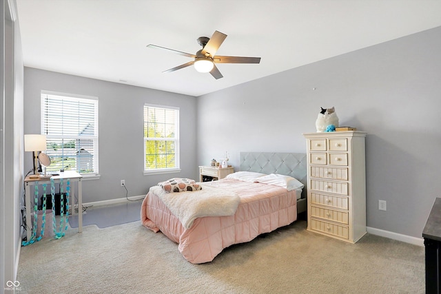 bedroom featuring light colored carpet, baseboards, and a ceiling fan