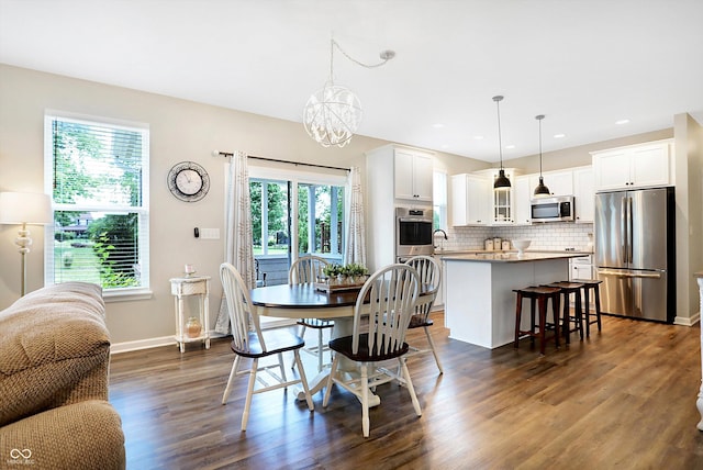 dining space featuring dark wood-type flooring, baseboards, recessed lighting, and a notable chandelier