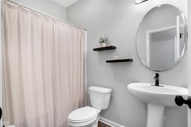 bathroom featuring baseboards, toilet, curtained shower, and a sink