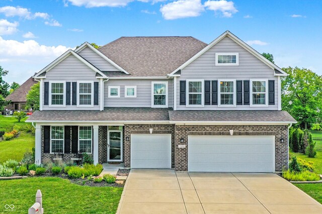 view of front of home featuring a garage, a front yard, brick siding, roof with shingles, and driveway