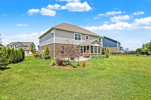 rear view of property with a sunroom, a patio area, and a yard