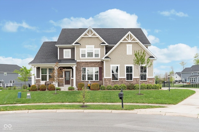 craftsman-style house with roof with shingles, fence, and a front yard