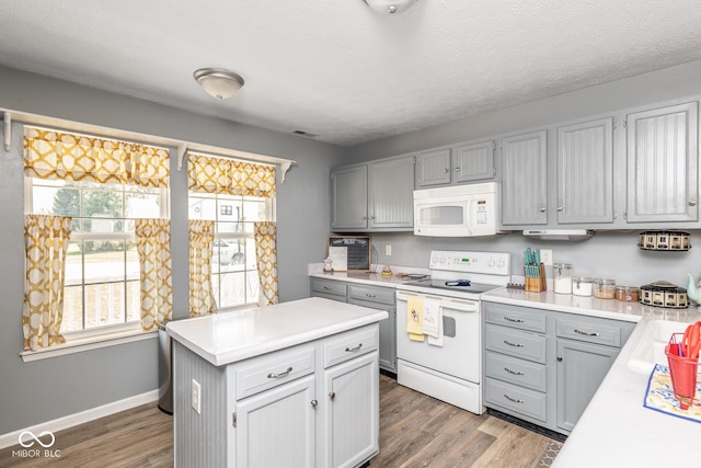 329 Dogwood Dr, Pendleton, IN 46064 - kitchen featuring white appliances, light countertops, wood finished floors, gray cabinets, and a center island