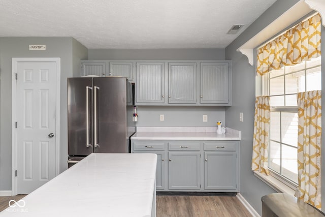 329 Dogwood Dr, Pendleton, IN 46064 - kitchen featuring high end refrigerator, gray cabinets, wood finished floors, healthy amount of natural light, and a textured ceiling