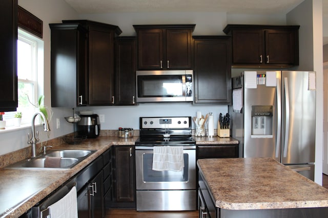 981 Redwood Dr, Franklin, IN 46131 - kitchen with appliances with stainless steel finishes, dark brown cabinetry, a center island, and wood finished floors