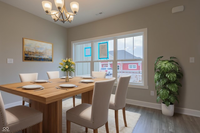 dining area with baseboards, visible vents, wood finished floors, and a notable chandelier
