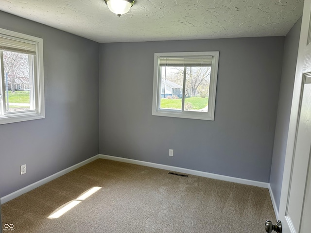 empty room with carpet, baseboards, a textured ceiling, and visible vents