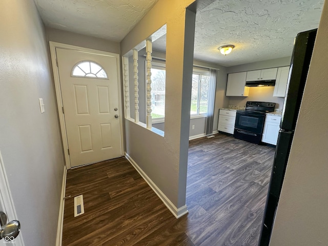 entryway featuring baseboards, visible vents, dark wood-type flooring, and a textured ceiling