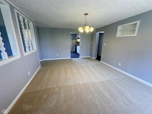 empty room featuring baseboards, a textured ceiling, carpet, and a notable chandelier