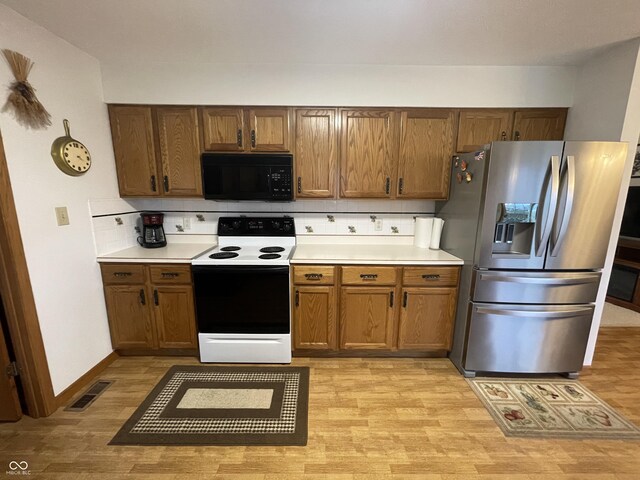 1310 Pin Oak Dr, Seymour, IN 47274 - kitchen with stainless steel fridge, range with electric stovetop, visible vents, light wood-style flooring, and black microwave
