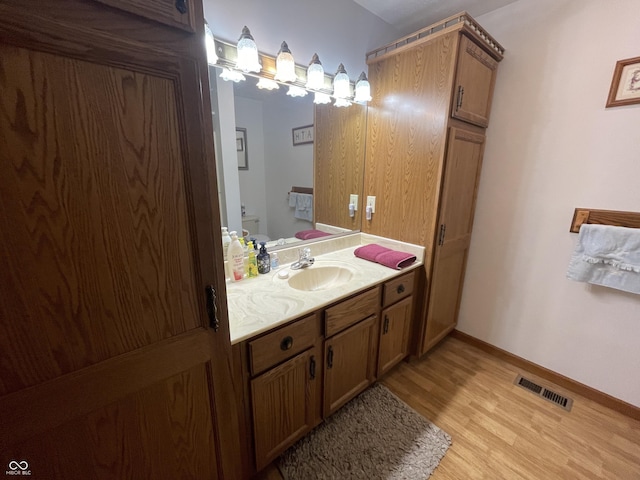 1310 Pin Oak Dr, Seymour, IN 47274 - bathroom featuring toilet, vanity, wood finished floors, baseboards, and visible vents