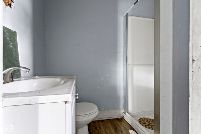 full bath featuring a stall shower, vanity, toilet, and wood finished floors