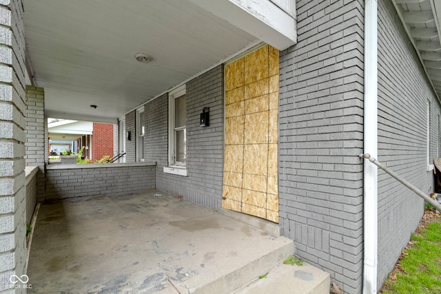 exterior space with an attached carport, a porch, and brick siding