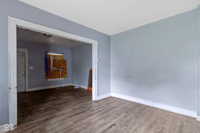 spare room featuring baseboards and wood finished floors